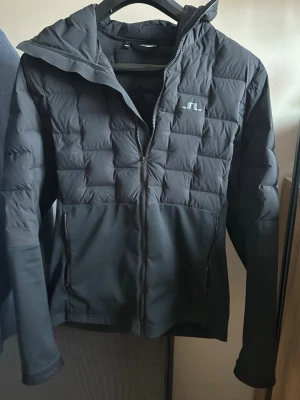 Svart pufferjacka från J.Lindeberg - Säljer en svart pufferjacka från J. Lindeberg. Hittar själv inte denna modell på nätet så den är väldigt unik. Lite smått nopprig längst ut på ärmen men annars som helt ny. Skriv vid frågor!😁