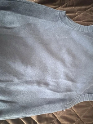 Blå stickad väst med blommor Sweet SKTBS - Säljer en blå stickad väst från Sweet SKTBS i storlek X-Small. Västen har ett coolt blommönster i beige och svart framtill, ribbade kanter vid hals och nederkant samt ärmlös design. Perfekt för lager-på-lager och att ge din outfit en unik touch.