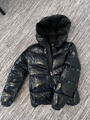 Colmar glansig jacka - Jag säljer en svart glansig jacka från Colmar. Jackan är i nyskick och bara använd ett fåtal gånger, passar som en xs/s.