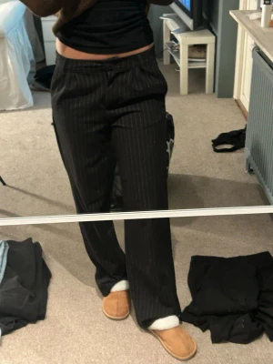 Svarta kostymbyxor med smala ränder - Säljer ett par svarta kostymbyxor med tunna vita ränder och baggy passform!!💓