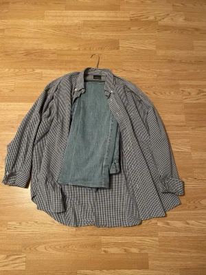 Rutig skjorta med jeans - Snygg rutig skjorta från Red/Green i svart och vitt. Klassisk krage, knappar framtill och långärmad modell. Tillverkad i bomull och polyester för en skön känsla och bra passform. Perfekt till jeans eller chinos. Säljes med ett par jeans i storleken W31, L32 dom är också oklart märke. Skjortan är en oklar storlek men skulle säga nånstans vid L,XL 