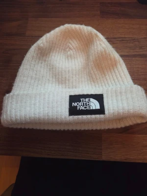 Vit ribbstickad mössa The North Face - Säljer en stilren vit ribbstickad mössa från The North Face som jag har användt 1 gång och är Onesize storlek. Den är väldigt skön och mjuk.Om du har några frågor är det bara att fråga.