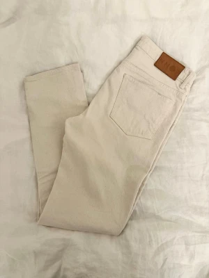 Krämvita jeans från NN07 modell:Johnny 1856 - Säljer ett par stilrena krämvita/vita jeans från NN07, modell Johnny 1856. Klassisk femficksmodell med rak passform och snyggt läderpatch bak i midjan. Tillverkade i kraftig bomull med en clean look som passar till allt.