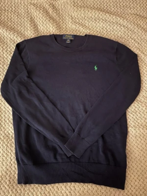 Marinblå tröja från Polo Ralph Lauren S - Klassisk svart tröja från Polo Ralph Lauren i storlek S. Tröjan har lång ärm och den ikoniska gröna broderade loggan på bröstet. Tillverkad i mjukt material som passar perfekt till höst och vinter. Enkel och stilren design som funkar till allt. Det står xl på lappen men jag uppskattar storleken till S-M så något måste ha blivit fel när tröjan producerasdes därav priset
