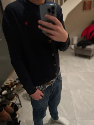 Riktigt mörkblå kofta från Morris i merinoull - Säljer en mörkblå kofta från Morris i 100% merinoull. Koftan har träknappar framtill, v-ringad hals och en liten röd broderad logga på bröstet. Perfekt för dig som vill ha en stilren och klassisk look med premiumkänsla. Denna är riktigt fräsch!