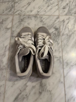 Grå Adidas Campus sneakers i mocka - Säljer ett par grå Adidas Campus sneakers. Änvända några gånger, så de har fortfarande bra skick. Köpta för runt 1000kr i London. 
