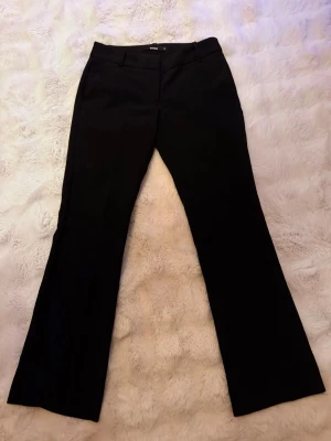 Svarta bootcut kostymbyxor BikBok - Säljer ett par svarta kostymbyxor från BikBok i storlek 32. Byxorna har bootcut-modell med klassisk dragkedja och knapp framtill samt hällor för bälte. Perfekta till en snygg och clean look.