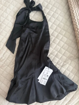 Svart halterneck topp i satin - Supersnygg svart halterneck topp från Gina tricot  i glansigt satinmaterial. Toppen har knyt i nacken, figurnära passform och lätt utsvängd nederkant. Perfekt för att lyfta vilken outfit som helst med en elegant touch. 