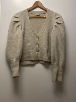 Beige kofta med puffärm och knappar - Mysig beige kofta! Liten fläck på vänstra tröjärmen men annars i bra skick!  vid frågor ❣️