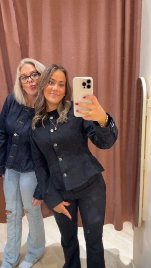 Svart jeansjacka  - Säljer en svart jeansjacka med snygg, figurnära passform och stora silvriga knappar framtill. Jackan har långa ärmar och markerad midja som ger en cool och modern look. Perfekt att styla med både jeans och dressade byxor för en trendig vibe. 