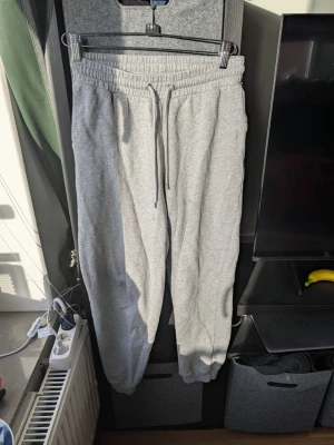 Grå mjukisbyxor från Monki, storlek S - Säljer ett par grå mjukisbyxor från Monki i storlek S. De har elastisk midja med snörning och ribbade muddar vid bensluten. Materialet är mjukt och skönt, perfekt för chill dagar. Klassisk loose passform och enkel design utan mönster.