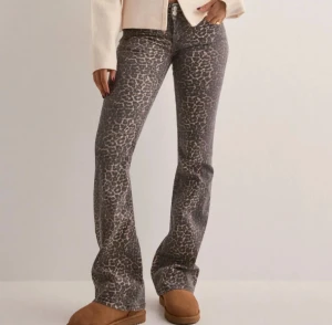 Leopardmönstrade bootcut jeans - Snygga bootcut jeans med leopardmönster i grå och beige toner. Byxorna har klassisk femficksdesign och normal passform, perfekta för dig som vill sticka ut med en cool look. Materialet är jeans och midjan är midwaist.