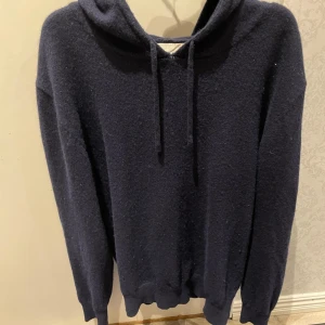 Mörkblå kashmir hoodie från Sayless - Säljer en stilren mörkblå hoodie från Sayless i mjuk kashmir.Perfekt för en avslappnad och bekväm stil. Riktigt snygg hoodie som passar till allt och till alla tillfällen. Modellen är ca 178