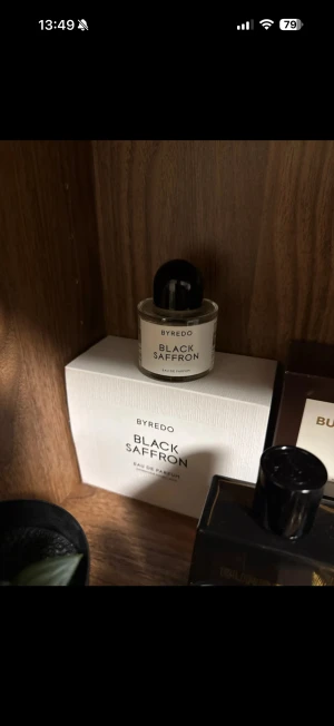Byredo Black Saffron EdP 50 ML – Säljes (billigt) - Säljer min Byredo Black Saffron Eau de Parfum – flaska med doft med härligt djup och karaktär.  Doftnoter: 	•	Toppnoter: Juniperbär, Pomelo, Safran   	•	Hjärtnoter: Svart viol (black violet), Kristallros (cristal rose), Läderackord   	•	Basnoter: Ljust trä (blonde woods), Hallon, Vetiver    Doften beskrivs ofta som orientalisk – woody, fruktig och något kryddig, med en balanserad mix av safran & citrus i början, ett elegant, något mystiskt hjärta, och en varm, träig & söt-fruktig bas som håller 