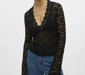 Svart spetsblus med v-ringning - Säljer en svart långärmad blus i spets med djup v-ringning och vågig kant. Toppen är inte helt genomskinlig på magen och bröstet utan har tyg under! 