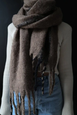 Brun ullig halsduk från Zara - Fast pris. Stor och mysig halsduk från Zara i brunmelerad ullmix med en bred mörkgrå rand och långa, tjocka fransar. Perfekt att vira flera varv runt halsen för en cool och avslappnad look. Materialet är fluffigt och ger en riktigt trendig vibe. Ny med prislapp. Storlek M. 250x28 cm.