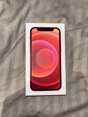 iPhone 12 mini - Snygg röd iPhone 12 mini i originalkartong. Telefonen har dubbla kameror och ser ut att vara i gott skick utan synliga repor eller skador på baksidan. Perfekt för dig som vill ha en kraftfull och stilren mobil. Laddare och tillbehör ingår ej, allt fungerar precis som vanligt förutom face-id❤️