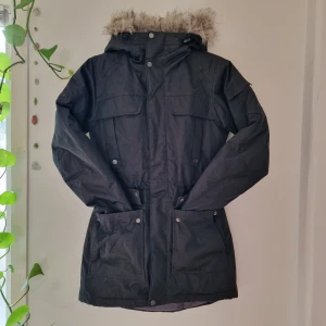 Svart vinterjacka/parkas från everest - Svart tjock och lång vinterjacka/parkas med avtagbar fakepäls. Polyesterfyllning: torkar snabbare och är cruelty free, 6 fickor fram, 1 innerficka och 1 ficka på armen, dragsko i midjan och i nederkant. Perfekt i skidbacken eller bara på kalla dagar. Pga flyttstäd behöver denna hitta ett nytt hem. Som ny, inga defekter. Mått: Ärm - 53 cm, Axelbredd - 42 cm, Längd - 75 cm. Nypris: 1499:-. 