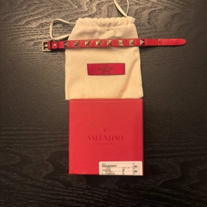 Rött Valentino Garavani bälte med nitar - Säljer ett riktigt fett armband från valentino i färgen röd, armbandet är såklart äkta och allt på kinden medföljs. Ny pris är cirka 3000 kr och mitt är 1299 men kan såklart diskuteras!!, hör av er vid frågor! Obs extra nitar medföljs 