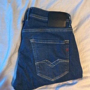 Blå Replay Hyperflex jeans ROCCO - Snygga blå jeans från Replay, modell Hyperflex Rocco med comfort fit. Klassisk femficksdesign, kontrastsömmar och Replay-logga på bakfickan. Jeansen är tillverkade i stretchigt denim för extra komfort och har en modern passform. 