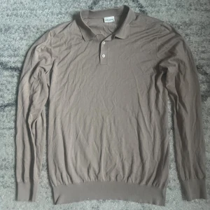 Beige långärmad pikétröja John Henric - Säljer en beige långärmad pikétröja från John Henric. Tröjan har klassisk krage, knäppning med två knappar och ribbade muddar vid ärmslut och nederkant. Perfekt för en clean och stilren look.