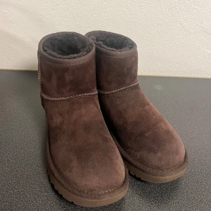 Bruna UGGs - Ett par mini II uggs i färgen chocolate, storlek 37. Skorna är lite vattenskadade vilket man ser på första bilden. Fodret är borta vid hälarna annars är det fortfarande fluffigt.