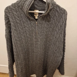 Grå kabelstickad tröja i ull från H&M premium  - Mysig grå stickad tröja i ullblandning med kabelstickat mönster. Perfekt för kyliga dagar och passar till allt. Oversize modell så passar även M.