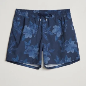 Blå blommiga badshorts från Ralph Lauren - Säljer ett par snygga blå badshorts från Ralph Lauren med blommigt mönster. Shortsen har elastisk midja med snörning och kommer med tillhörande påse. Perfekta för stranden eller poolen, riktigt stilrena och bekväma.