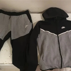 Nike tech Grå/Svart - En Nike tech tracksuit i färgen grå/svart . Hoodien är i storlek S och är i bra condition , byxorna är i storlek M och är lite noopriga i fickorna men annars bra condition. Bara att skriva för frågor eller om bilder👍