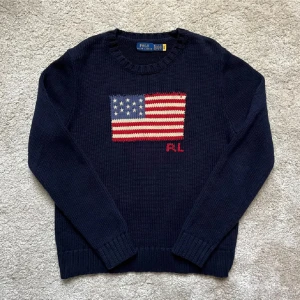 Ralph Lauren Flag Sweater - Supersnygg och populär Mörkblå Flag Sweater från Ralph Lauren. Unisex modell, passar lika bra oavsett vem som bär tröjan. Mycket fint skick, knappt använd. Inga defekter. Storlek XL, passar ungefär som en XS på killar och som en M/L på tjejer. Nypris 4800. Hör av er vid funderingar🙌🏻