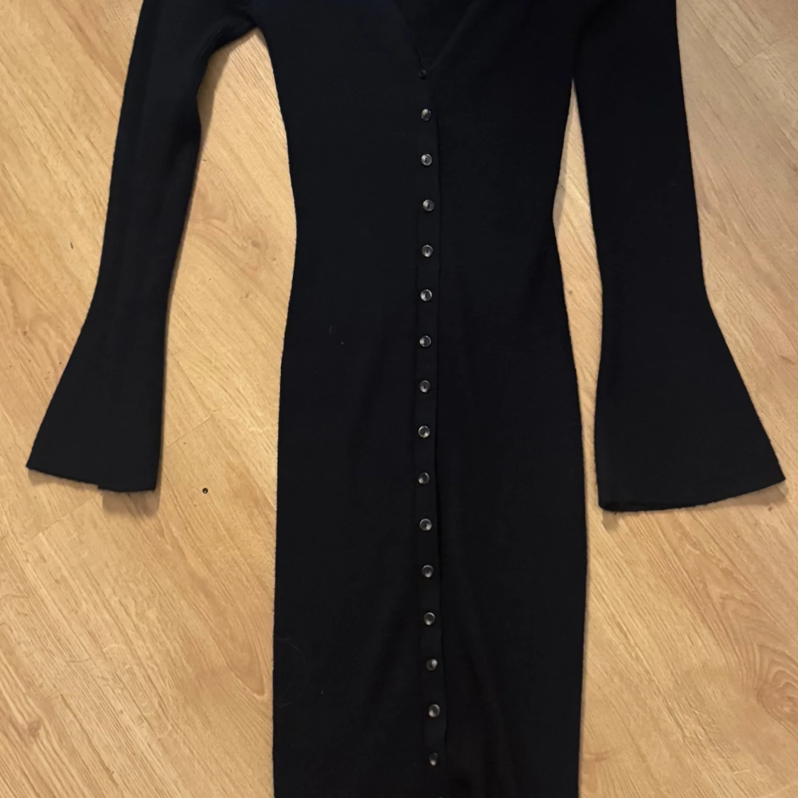 Svart långärmad klänning med utsvängda ärmar och knappar