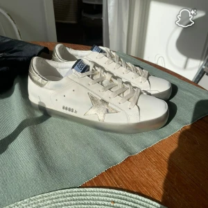 Golden Goose vita sneakers med guldstjärna - Golden Goose sneakers i vitt skinn med metallicguld detaljer och ikonisk stjärna på sidan. Små i storlek, passar till 38/39. Priset kan diskuteras vill bara bli av med de. 