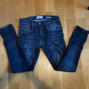 Mörkblå Replay Anbass jeans slim fit - Snygga mörkblå Replay Anbass jeans med slim fit. Klassisk femficksmodell med diskreta slitningar och snygga detaljer på bakfickorna. Jeansen är tillverkade i stretchigt denim för en bekväm passform och har en modern, smal siluett.
