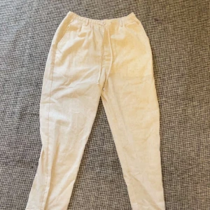 Beiga linnebyxor från Coofandy S - Snygga beiga linnebyxor från Coofandy i storlek S. Byxorna har elastisk midja med snörning och raka ben. Perfekta för en chill och avslappnad stil, tillverkade i ett luftigt linnematerial som passar bra till varmare dagar. Aldrig använda lappen kvar