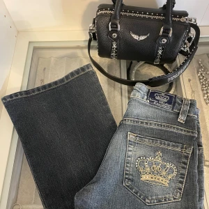 Victoria Beckham bootcut jeans - Snygga blå bootcut/utsvängda jeans från Victoria Beckham med broderade kronor på bakfickorna och glittrig logga längs benet. Storlek 140. Nypris över 1000kr!