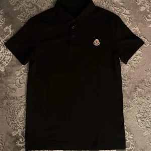 Moncler piké  - Snygg svart oanvänd Moncler pikétröja slim fit med liten broderad logotyp på bröstet. Stilren klass piké helt oanvänd ett riktig bra kap, pris kan diskuteras vid snabb affär.