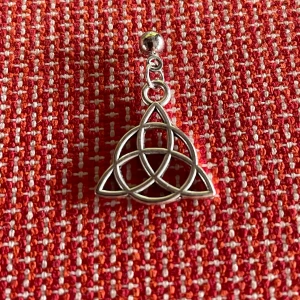 By prisförslag- 1 st Silvrigt örhänge med keltisk knut - Unikt örhänge i silverfärgad metall med en öppen keltisk knut-design. Hängsmycket har en snygg geometrisk form och sitter fast i en liten kula. Perfekt för dig som gillar symboliska och stilrena smycken.