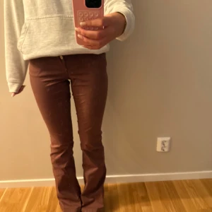 Bruna bootcut manchesterbyxor - Säljer ett par bruna lågmidjadejeans med bootcut-modell. Byxorna har klassisk femficksdesign, normal passform och stängs med knapp och dragkedja. Perfekta för dig som gillar retrovibbar och vill ha något som sticker ut lite extra. Står storlek 30 men jag brukar ha storlek xs-s och 32-34 och 25-27 för referens🩷