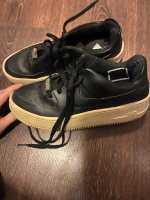 Nike Air Force 1 svart  - Snygga Nike Air Force 1 sneakers i svart läder med vit sula. En ganska hög sula men väldigt snygg!! Använder dom tyvärr inte längre! Behövs tvättas lite men de kan jag stå för! Bara att skriva för funderingar och går att diskutera priset!💗💗