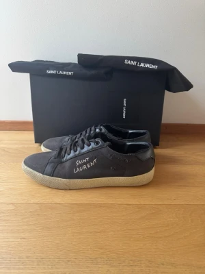 Svarta Saint Laurent sneakers - Riktig snygga svarta Saint Laurent för ett bra pris. Dem är i gott skick och alla tillbehör på bilden ingår. Priset kan diskuteras vid snabb affär. Finns lite slitningar men inget som påverkar skorna. 