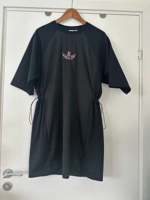Svart Adidas klänning, storlek S / M - Helt NY svart klänning från Adidas med broderad logga framtill. Klänningen har dragsko i midjan för justerbar passform och korta ärmar. Storleken säger storlek S, men tycker den passar bra till både M och XS också eftersom man kan justera midjan.   Hämtas i Stockholm eller skickas mot porto. 