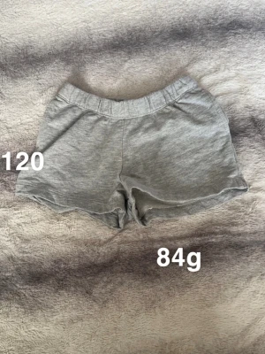 Grå bomullsshorts med resårmidja - Mysiga grå shorts med elastisk midja och avslappnad passform. Perfekta för varma dagar eller som chill-plagg hemma. Klassisk enkel design utan synliga detaljer.🌸 Fint använt skick. Storlek 120