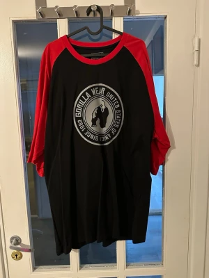 Gorilla Wear svart/röd t-shirt - Snygg svart t-shirt från Gorilla Wear med röda trekvartsärmar och kontrastfärgade sömmar. Stor logga med gorilla-tryck framtill och mindre logga bak i nacken. Perfekt för dig som gillar sportig och avslappnad stil.