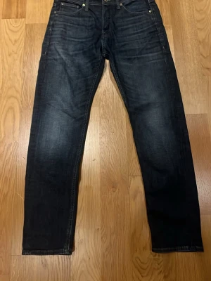 Mörkblå Jack & Jones raka jeans tapered/ Mike W29 L32 - Säljer ett par mörkblå jeans med klassisk femficksdesign och raka ben. Jeansen har en snygg tvätt med lätt slitningar framtill och bakfickor. Perfekta till en avslappnad stil.