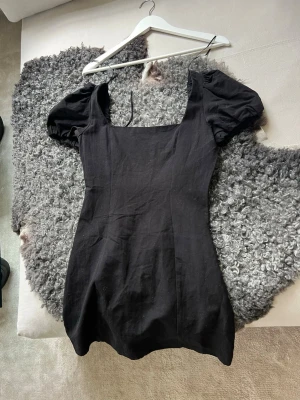 Svart klänning med puffärmar - Trendig svart klänning från Zara med puffärmar och fyrkantig urringning. Klänningen har snörning i ryggen för en justerbar passform och är figurnära i modellen. 