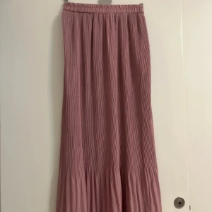 Plisserad rosa långkjol / maxikjol - En plisserad långkjol. Köpt utomlands. Kjolen har resår i midjan och ett volangparti längst ner som ger extra flow. Strl M men passar mig med S/xs, är elastisk i midjan så kan nog passa mindre och större eventuellt.