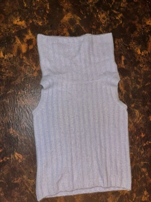 Ljuslila tröja i angora- och ullblandning - Ljuslila ribbad polotopp med hög krage och ärmlös design. Toppen är stickad i mycket mjukt material, 24% angora och 4% ull.