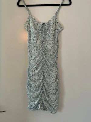 Blommig miniklänning - Söt klänning från HM.  Scrunch som ger smickrande passform Använd fåtal gånger Inga anmärkningar 