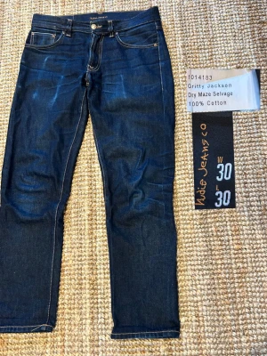 Nudie Jeans Selvedge  - Säljer mina Nudie Jeans Selvedge, i modellen Gritty Jackson och storleken är 30/30.   Här är måtten 👇 Innerbenslängd: 70 cm Totallängd: 98 cm Midja: 41 cm Benslut 18 cm  Jeansens selvedge-denim är riktigt snygg och håller formen bra, och de får en fin naturlig patina ju mer man använder dem! 	 Fråga gärna om du vill ha fler bilder!  Priset är ej hugget i sten!  Kolla min profil för liknande plagg! 😊