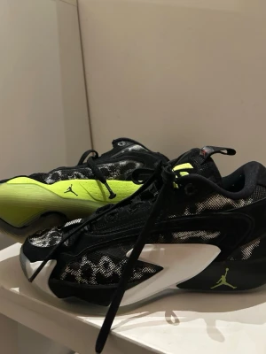 Jordan sneakers svart/vit/neongul - Säljer ett par Jordan sneakers i svart, vitt och neongult med coolt rutigt meshmönster på ovandelen. Skorna har snörning, låg profil och tydliga Jumpman-loggor på sidan och sulan. Perfekta för dig som vill sticka ut med en sportig vibe.